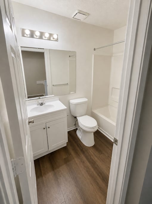 A white bathroom with a toilet, sink, and mirror.