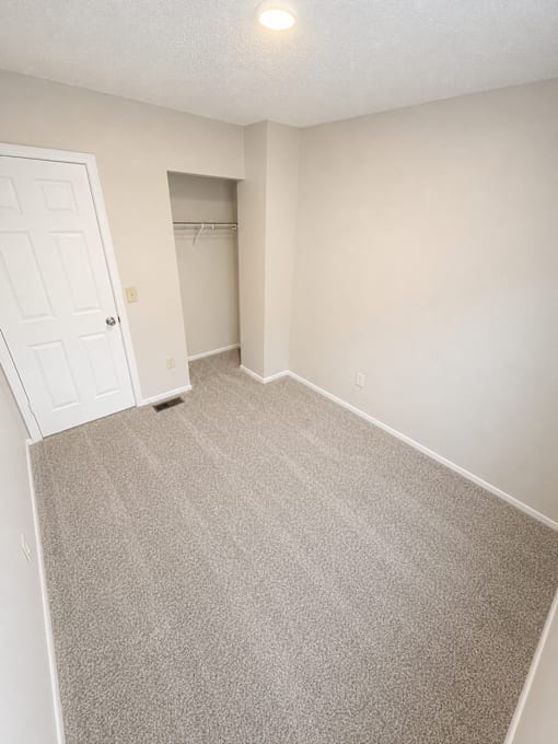 A room with a carpeted floor and a white door.