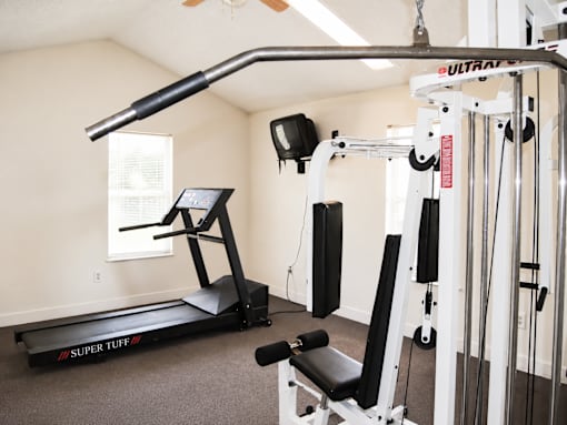 A home gym with a treadmill, weights, and exercise equipment.
