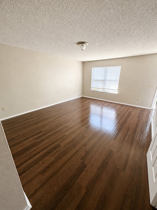 A room with wooden floors and a window with blinds.