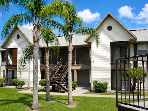 A white two-story apartment building with a balcony and a staircase.