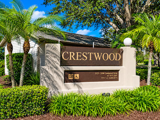 A sign that says Crestwood in front of some trees.