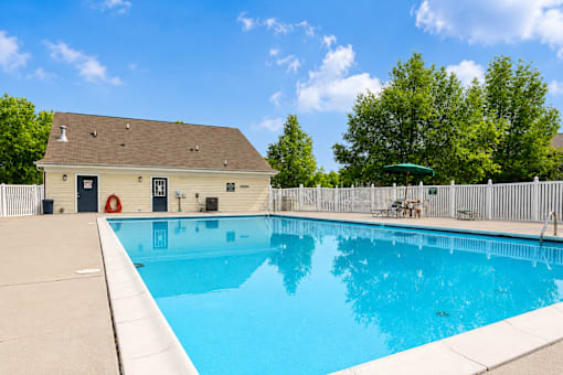 A small pool in a backyard with a white fence.