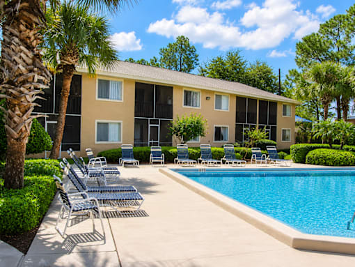 A pool area with chairs and a building in the background.