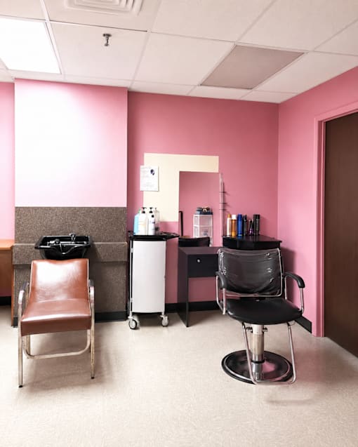 A room with a pink wall and a brown chair.