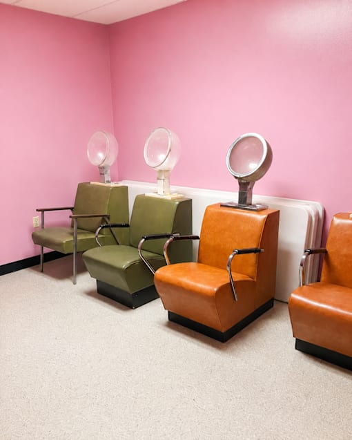 Three chairs and two mirrors in a room.