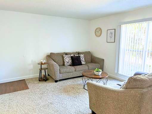A living room with a couch, a coffee table, and a clock on the wall.