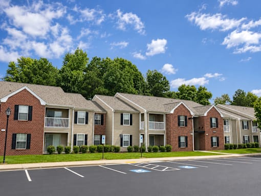A row of apartment buildings with a parking lot in front.