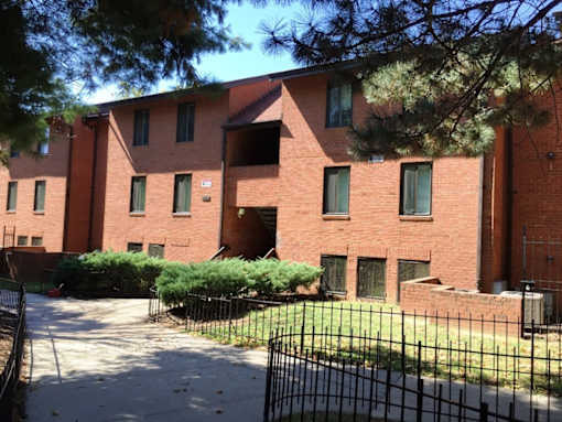 A red brick building with a black fence in front.