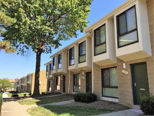 A tree is in front of a building with windows.