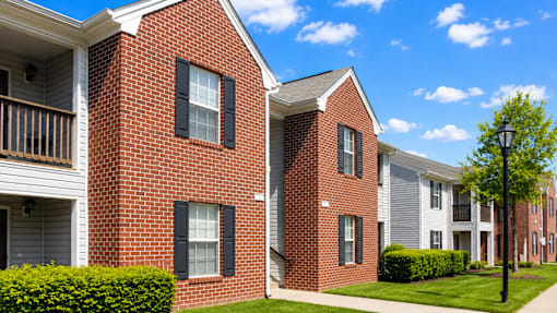 A row of red brick houses with green bushes in front.
