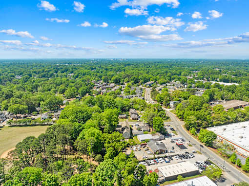 A bird's eye view of a small town with a mix of residential and commercial buildings surrounded by dense greenery.