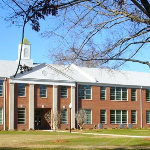 A large red brick building with a white tower and a clock on the front.