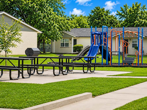 A playground with a blue slide and picnic table.