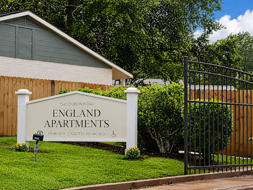 A sign for England Apartments is in front of a building.