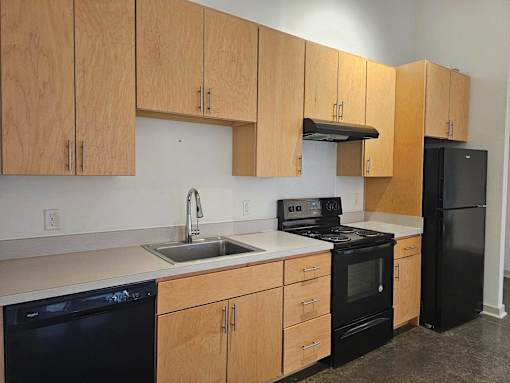 A kitchen with black appliances and wooden cabinets.at South Main Artspace Lofts, Memphis, TN 38126