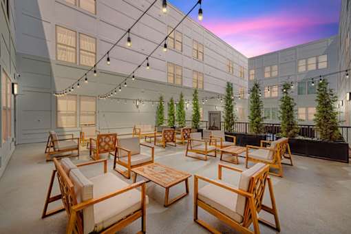 A patio with wooden furniture and string lights.