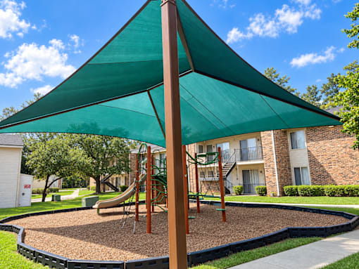 A playground with a green canopy and a slide.
