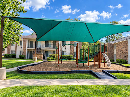 A playground with a green canopy and a slide.