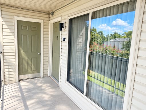 A white house with a green door and a sliding glass door.