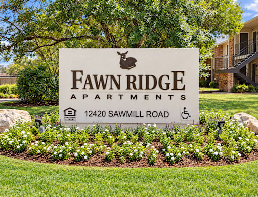 A sign for Fawn Ridge Apartments is surrounded by flowers.