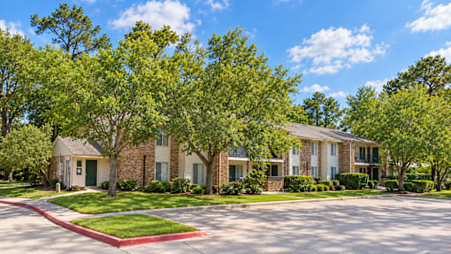 A row of houses with green trees in front.
