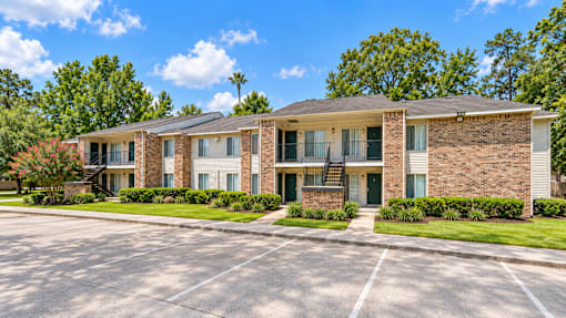 A brick apartment building with a green lawn in front.
