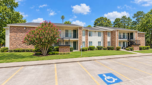 A parking lot with a handicap parking space in front of a brick building.