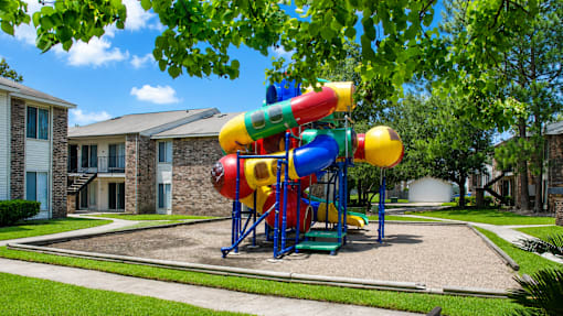 A colorful playground structure with a slide in the middle of a grassy area.