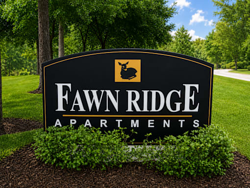A sign for Fawn Ridge Apartments is shown in front of a green lawn.