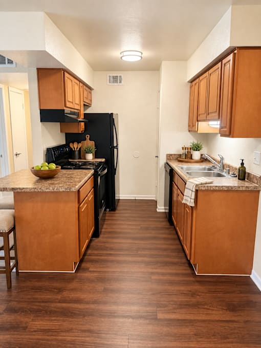 A kitchen with wooden cabinets and a black refrigerator.