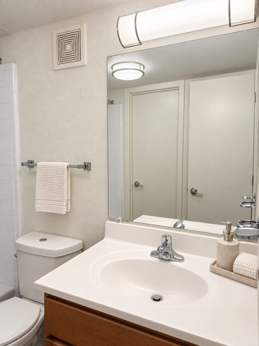 A white bathroom with a toilet, sink, and mirror.