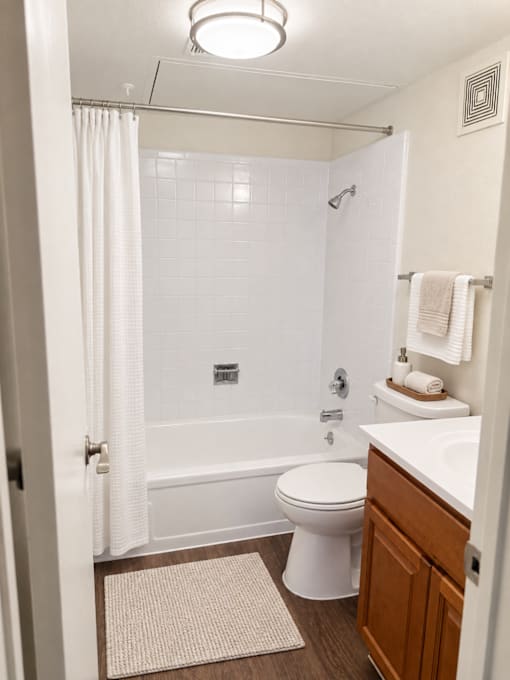 A white bathroom with a toilet, sink, and shower.
