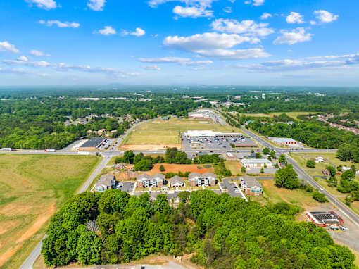 A bird's eye view of a residential area with houses, roads, and greenery.
