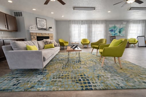 A living room with a grey couch, yellow chairs, and a blue rug.
