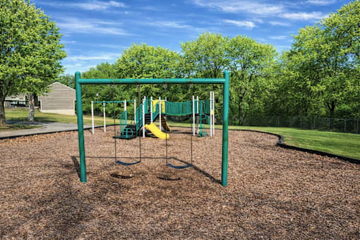 A playground with a green swing set and a yellow slide.