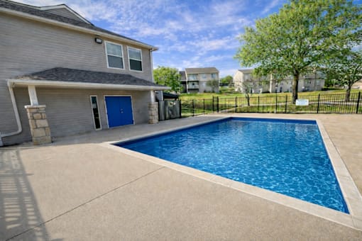 A residential house with a blue door and a pool in the backyard.