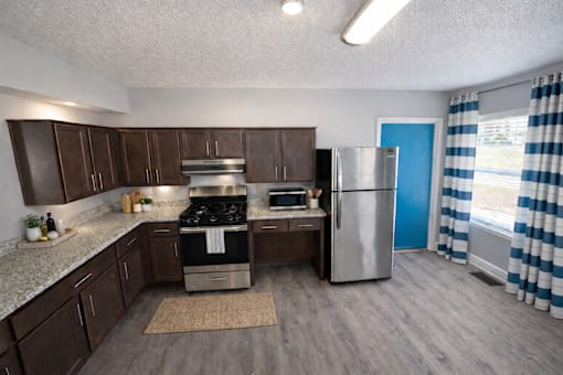 A kitchen with a stove, refrigerator, and cabinets.