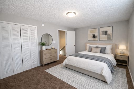 A bedroom with a large bed, a dresser, and a mirror.