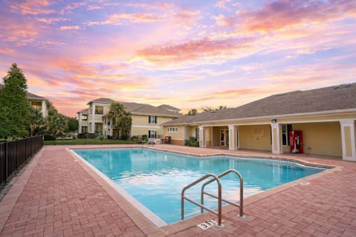 A swimming pool surrounded by a brick walkway and a fence.
