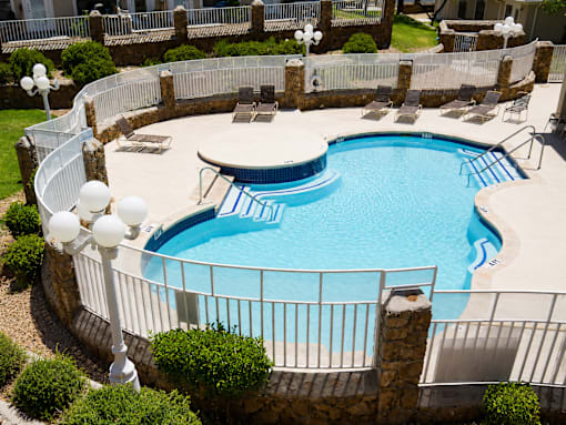 A round swimming pool surrounded by a fence and a stone wall.