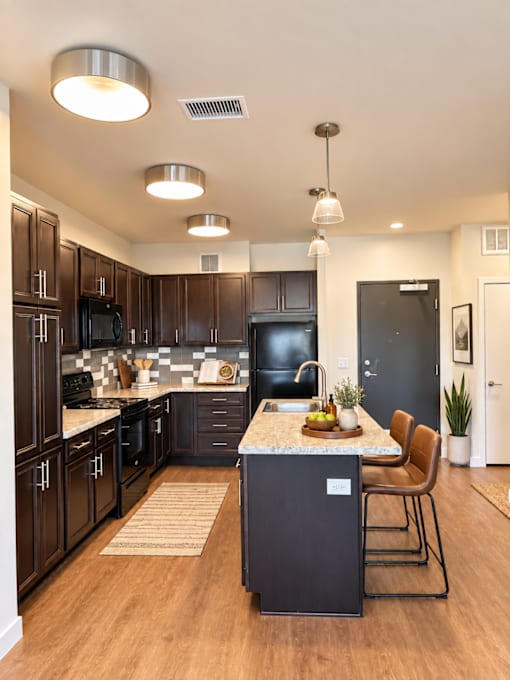 A modern kitchen with dark wood cabinets and black appliances.