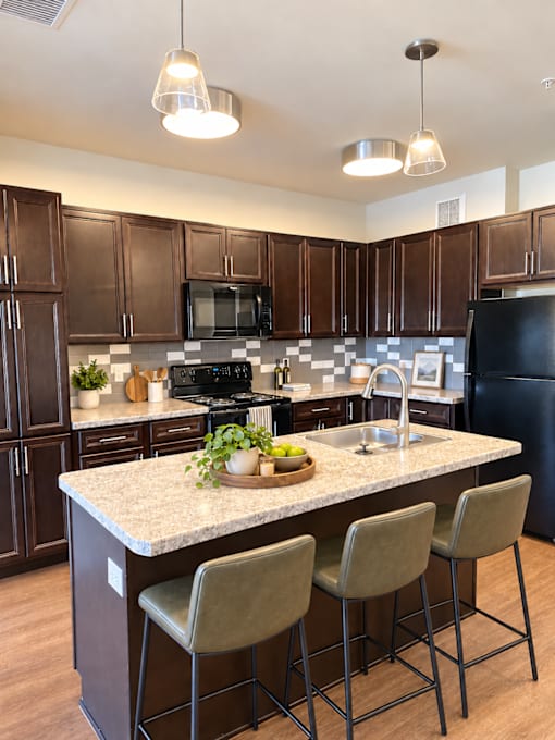 A kitchen with brown cabinets and a black refrigerator.