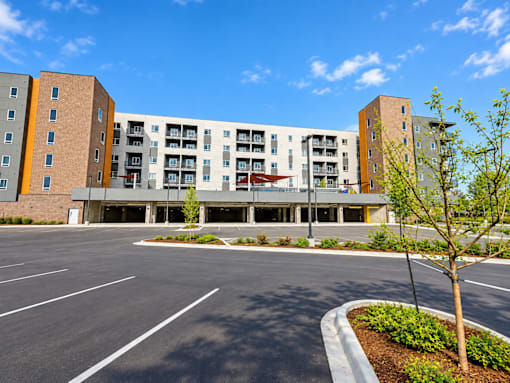 A parking lot in front of a multi-story apartment building.