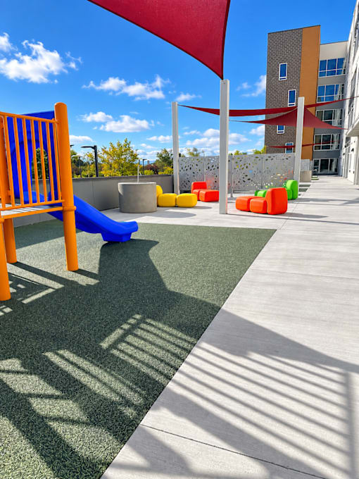 A playground with a blue slide and a red flag.