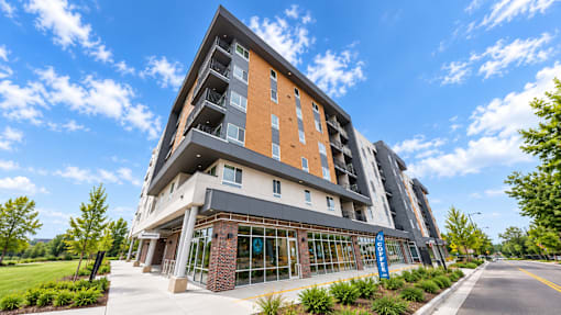 A modern multi-story building with a glass entrance and a brick base.
