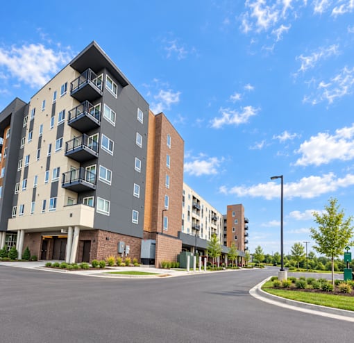 A modern apartment building with a parking lot in front.