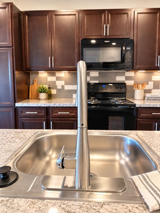 A kitchen with a stove, sink, and cabinets.