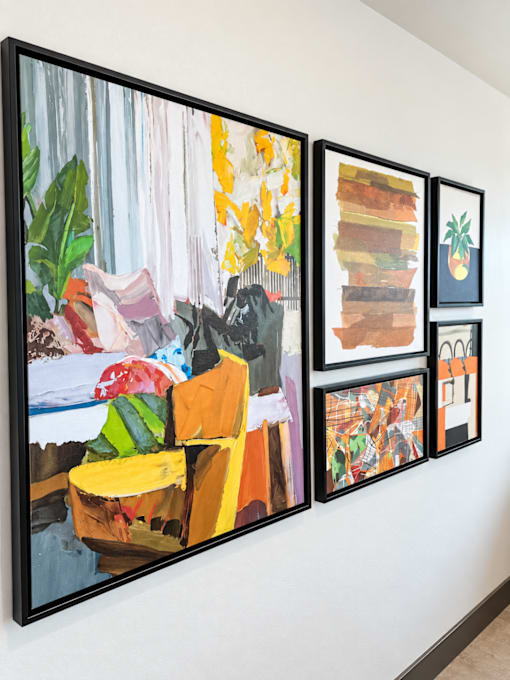 A wall with a painting of a yellow chair and a painting of a pineapple on it.