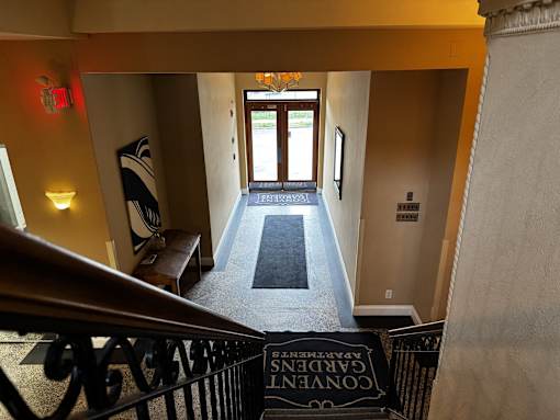 A hallway with a black railing and a black and white mat on the floor.